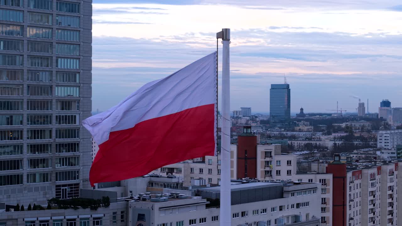 Polish flag waving on a tall flagpole in Warsaw city center, shot in slow motion