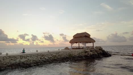 AERIAL---Person-doing-yoga-next-to-a-cabana-in-Cancun,-Mexico,-spinning-shot