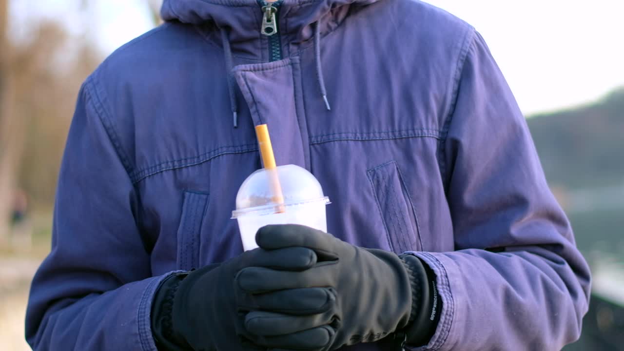 Man's hands walking and holding a cup with ice coffee and bamboo straw