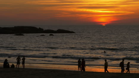 Sun-Dipping-Below-Horizon-Observed-by-People-in-Silhouette,-Sunset,-Goa,-India