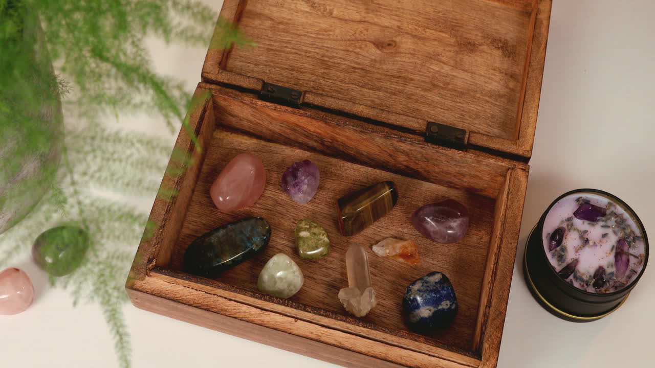 A wooden box full of healing crystals with an amethyst candle