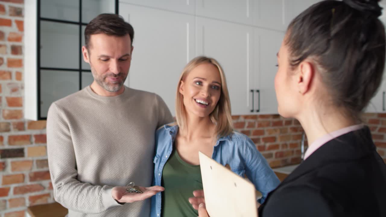 Close up video of realtor giving house keys to couple