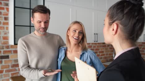 Close-up-video-of-realtor-giving-house-keys-to-couple