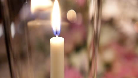 close up, single thin candle stick flaming inside glass at wedding celebration