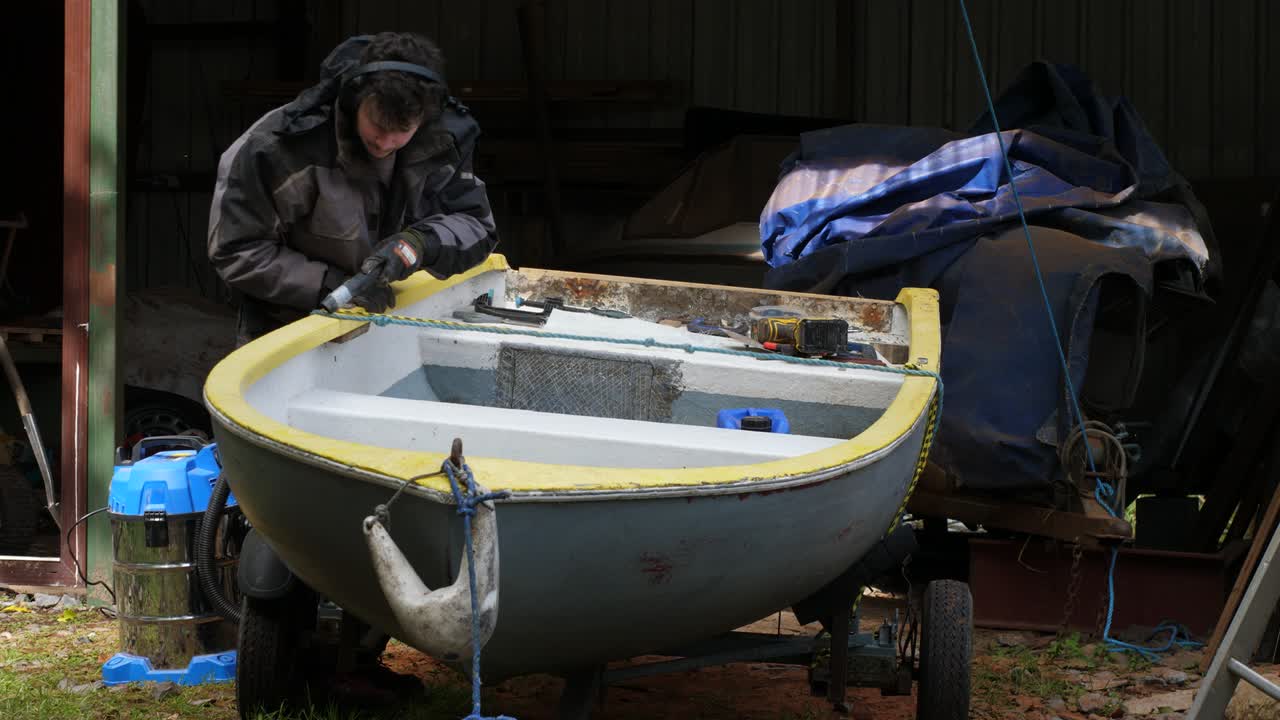 Young man repair small fiberglass boat vacuuming it out