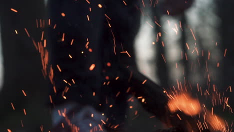 man pulls knife out a wood lock at bonfire close up sparks outdoor wilderness