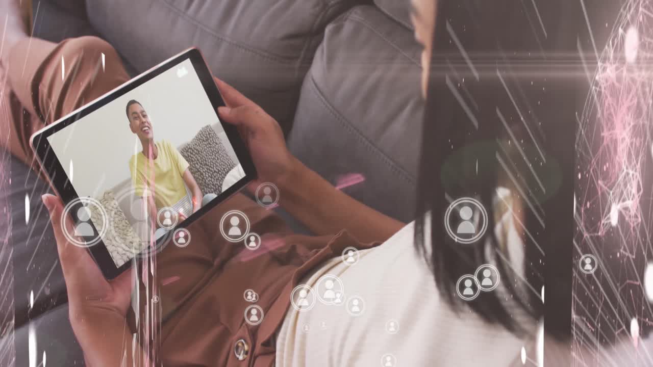 múltiples iconos de perfil flotando contra una mujer que tiene una videollamada en una tableta digital en casa