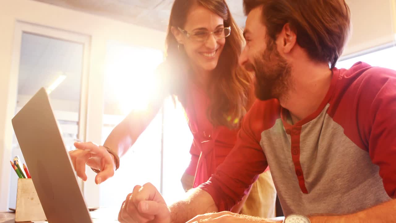 diseñadores gráficos masculinos y femeninos interactuando mientras trabajan