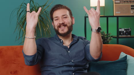 Overjoyed young lebanese man showing rock n roll gesture cool sign dancing rejoicing in success