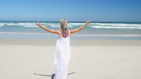 mujer mayor feliz caminando por la playa