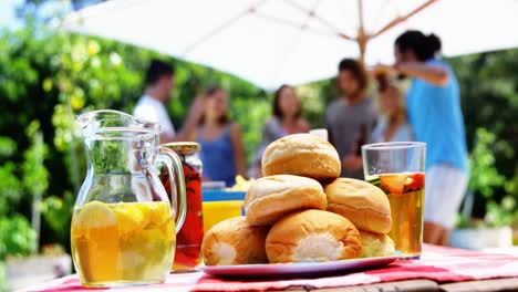 close-up of juice and buns served on table at outdoors barbecue party