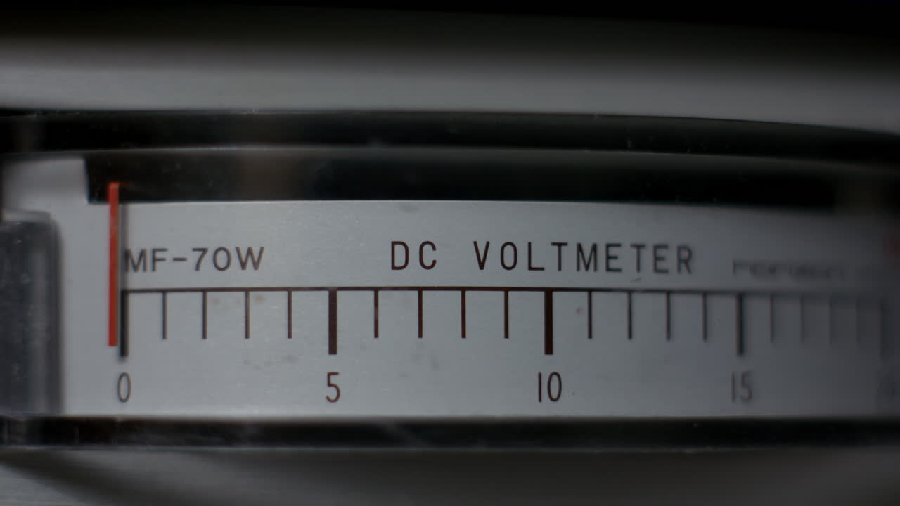 Nærbillede af et analogt DC-voltmeter på et vintage strømforsyningsapparat til laboratoriebrug, der viser nålen stige fra nul til tolv volt, hvilket symboliserer elektrisk test, strømstyring og teknisk måling