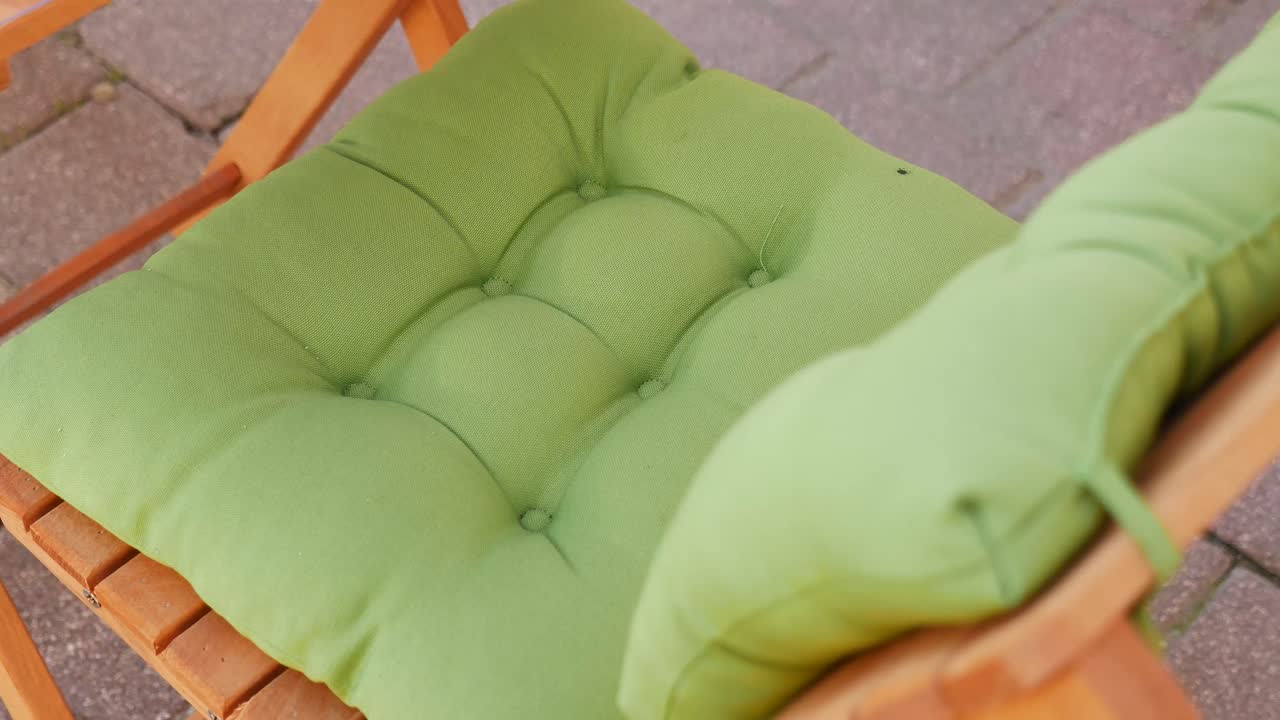 Primo piano di un cuscino verde su una sedia di legno
