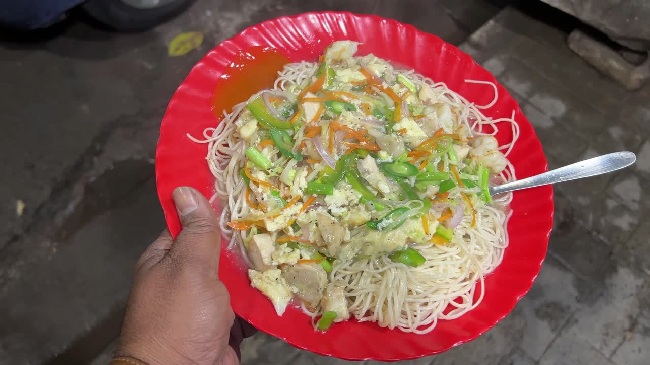 Closeup shot of veg gravy chowmein served with lots of green veggies on top.
