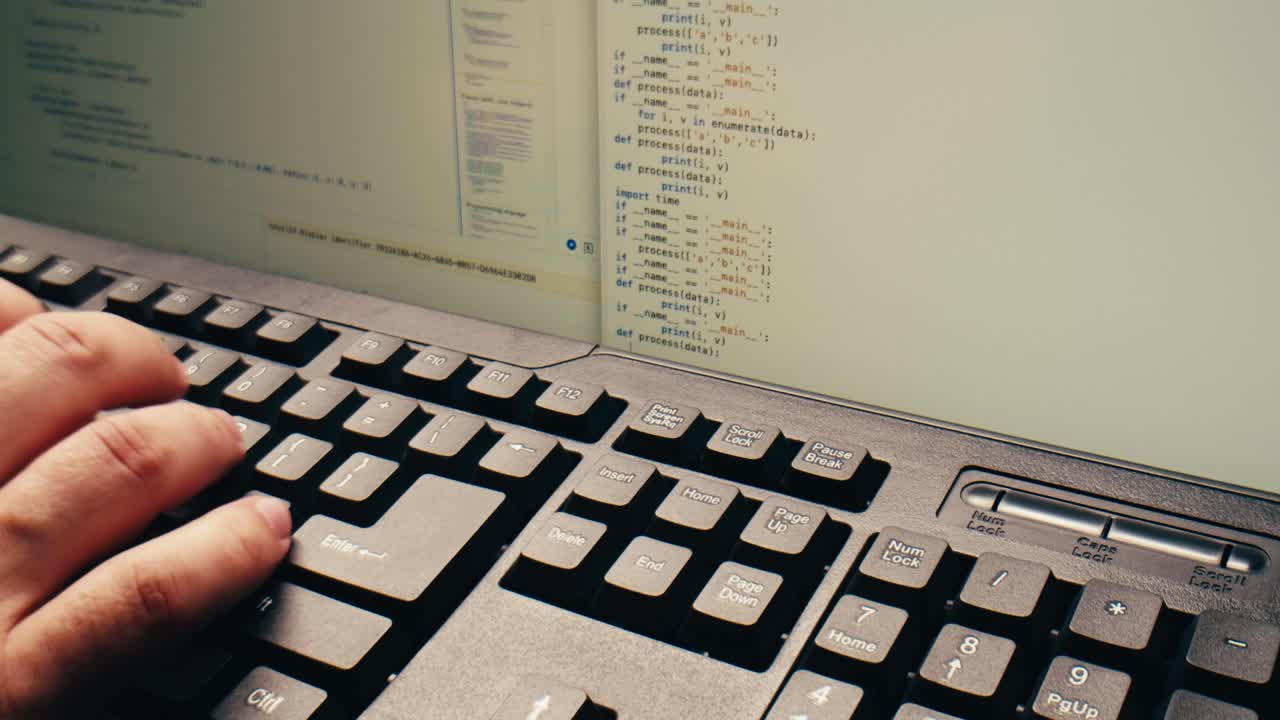 Hand Typing on Keyboard with Code on Computer Screen