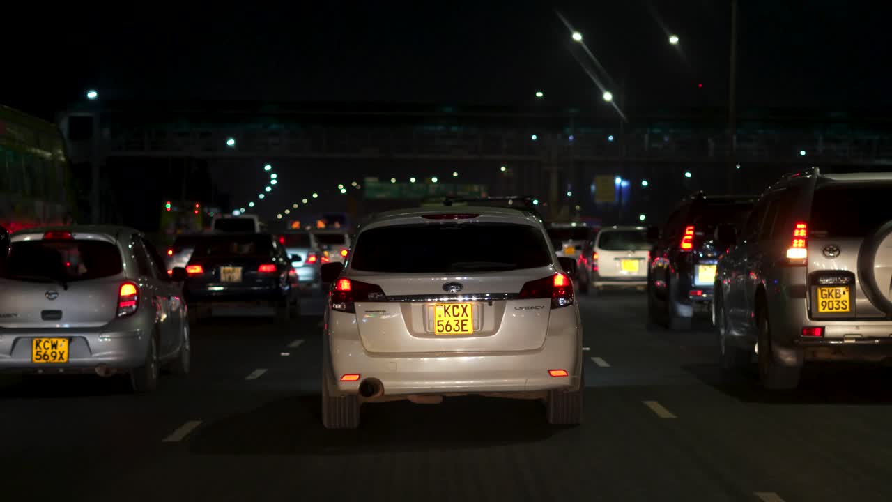 Busy nighttime traffic on Nairobi Highway, vehicles with headlights on, dark urban roadway