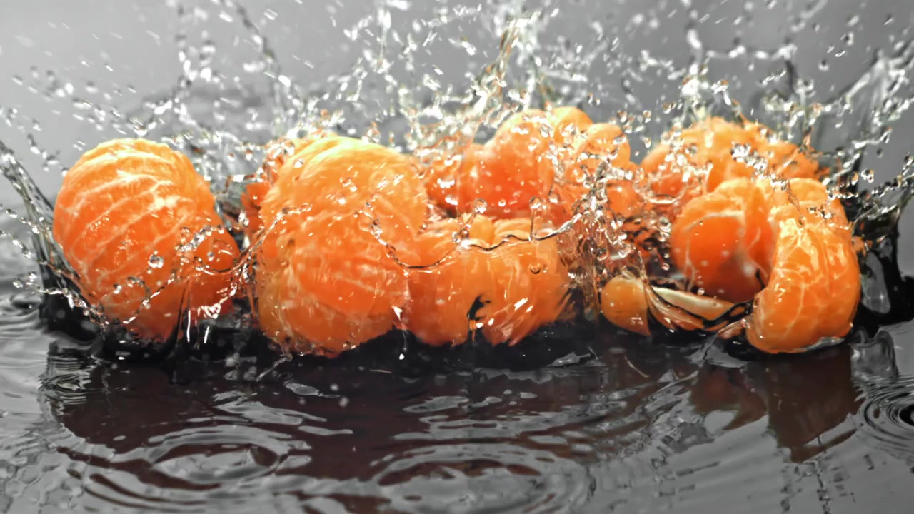 Pillede mandariner, der plasker ned i vand i slowmotion