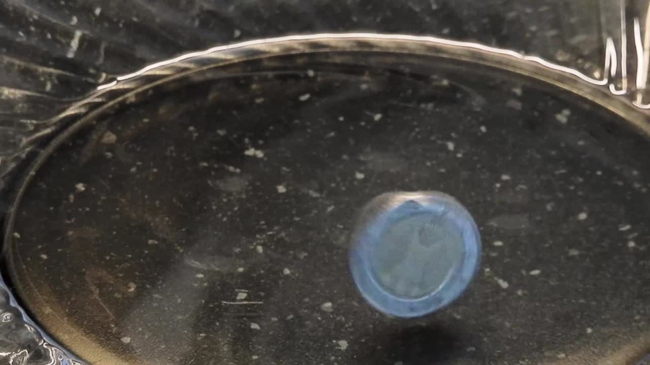 4k 영상 30fps 2 유로 동전 일어서서 유리 접시에 미친 것처럼 휘어지기 시작합니다.