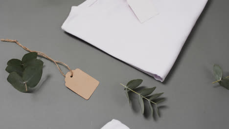 video of flat lay of white t shirts with tags and copy space on grey background