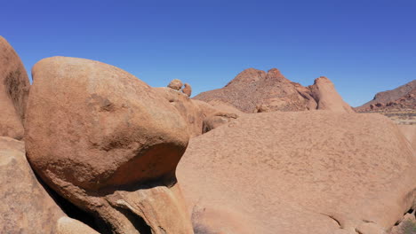 aerial shot revealing a person inside the dramatic natural stone arch of spitzkoppe, namibia