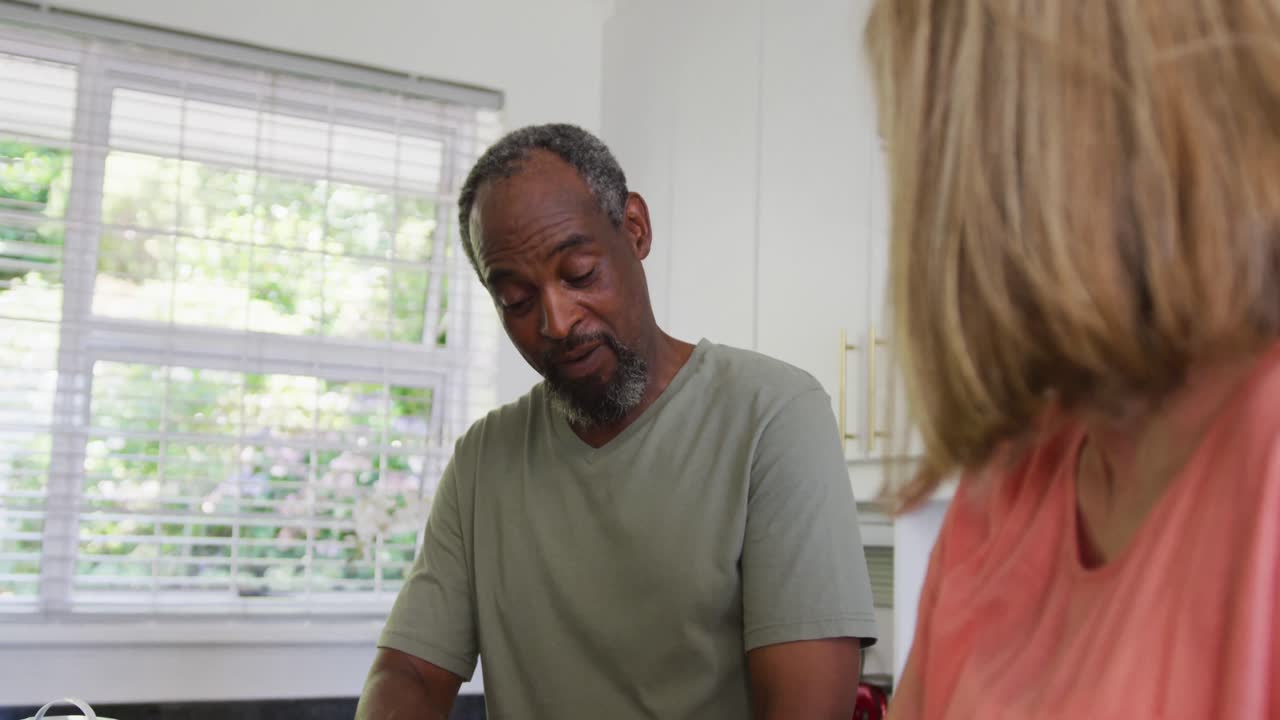 Happy diverse senior couple preparing food in kitchen and talking