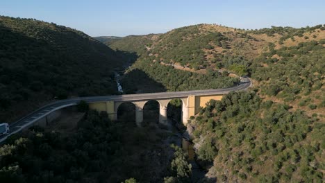 aerial of monheca bridge, truck crosses during a warm sunset, portugal, castelo branco, ladoeiro