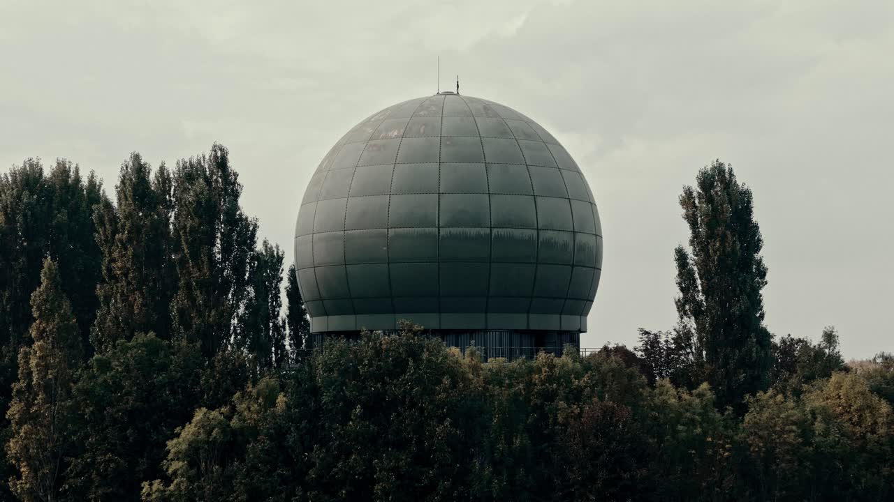 Large Radar Dome Structure Rising Above a Forest Under Overcast Sky
