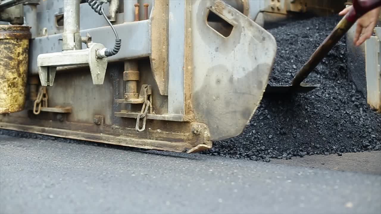 Compressing, compacting, leveling and smoothing the asphalt road surface using a Asphalt Paver Finisher