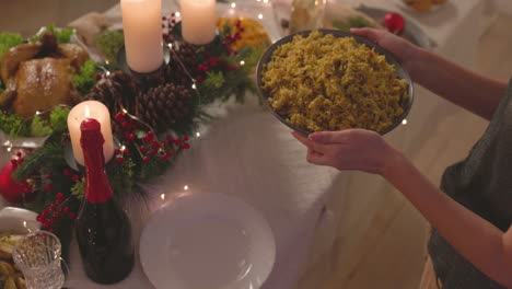 mujer irreconocible poniendo delicioso arroz en la mesa de la cena de navidad