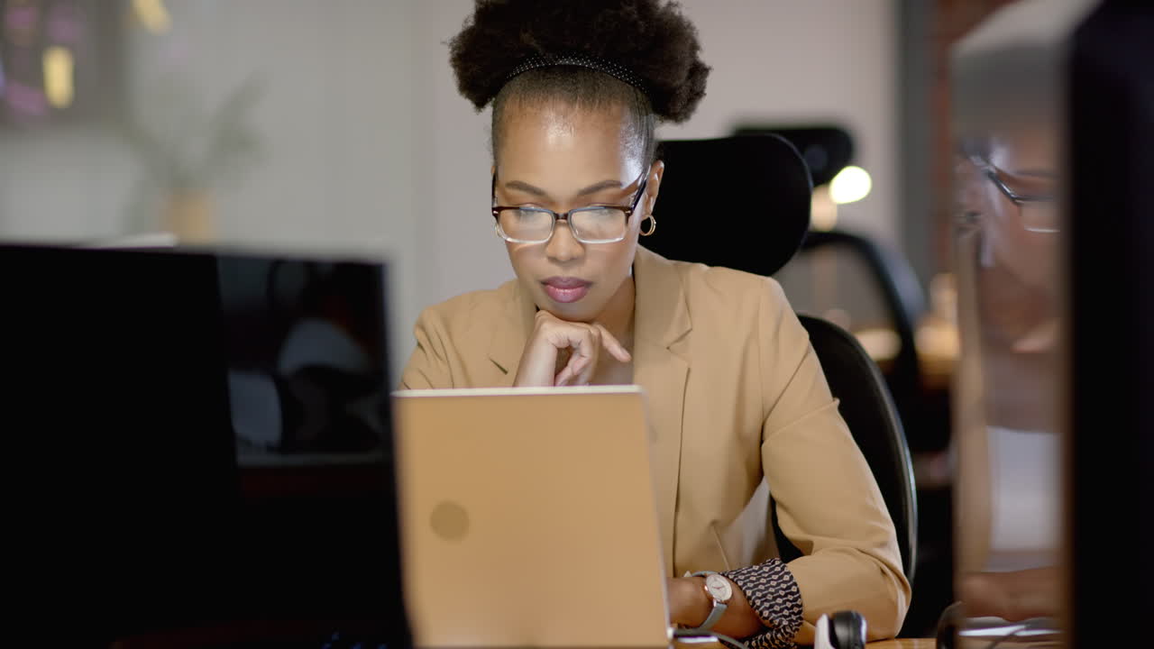 African American woman focuses intently on her business laptop screen at the office