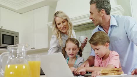 family using laptop together in kitchen
