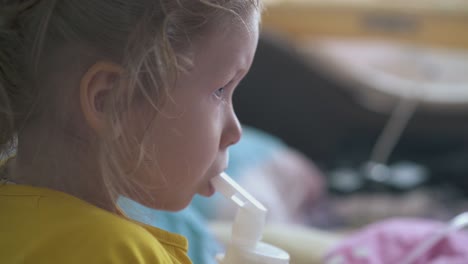 pretty small girl breathes with inhaler lying in bed at home