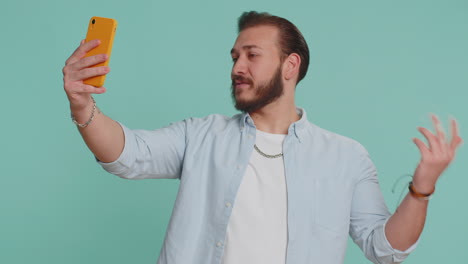 Lebanese-man-traveler-blogger-taking-selfie-on-smartphone-communicating-video-call-online-stream