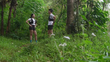asian couple resting and talking during outdoor workout in forest trail