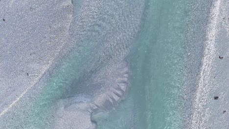 aerial footage captures the intricate patterns of a river in glenorchy, new zealand, highlighting turquoise waters and sandy textures