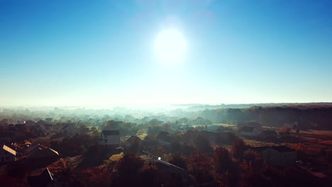 aerial top view of the small houses at sunrise. rural landscape of house roofs, roads and tree tops in spring or summer day. camera moves forward.