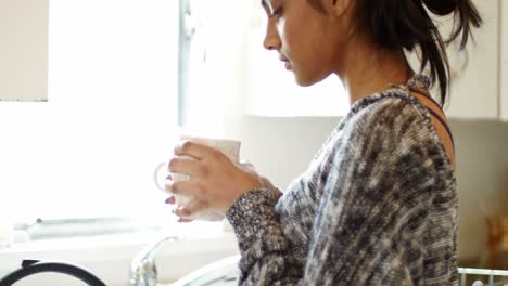 Woman-having-cup-of-coffee-in-kitchen