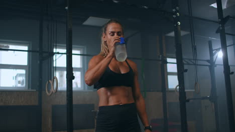 athletic-woman-in-the-gym-with-a-bottle-of-water-drinking-after-training-checks-the-pulse-on-the-sports-watch.-heart-rate-monitoring