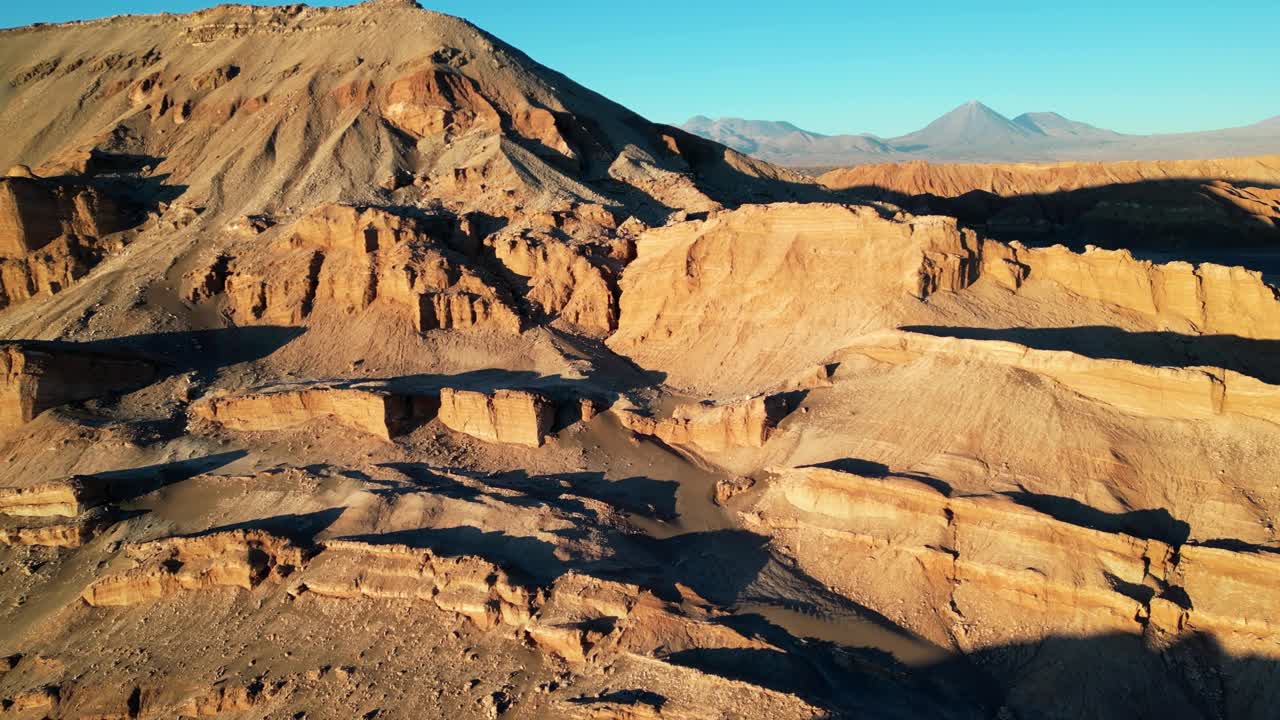 4K drone shot of orange ridgelines and salt deposits creating a surreal landscape in Chile’s Atacama Desert at dusk