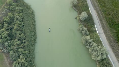 Pequeña-Lancha-Bajando-Por-Un-Río-Verde---Vista-Aérea-Recta-Hacia-Abajo