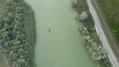 pequeña lancha bajando por un río verde - vista aérea recta hacia abajo