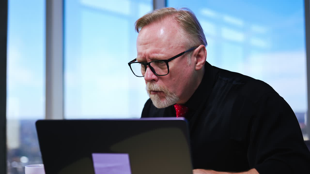Busy working man looking concentrated and puzzled. Entrepreneur looks at his laptop trying to figure out something. Close up. Blurred backdrop.