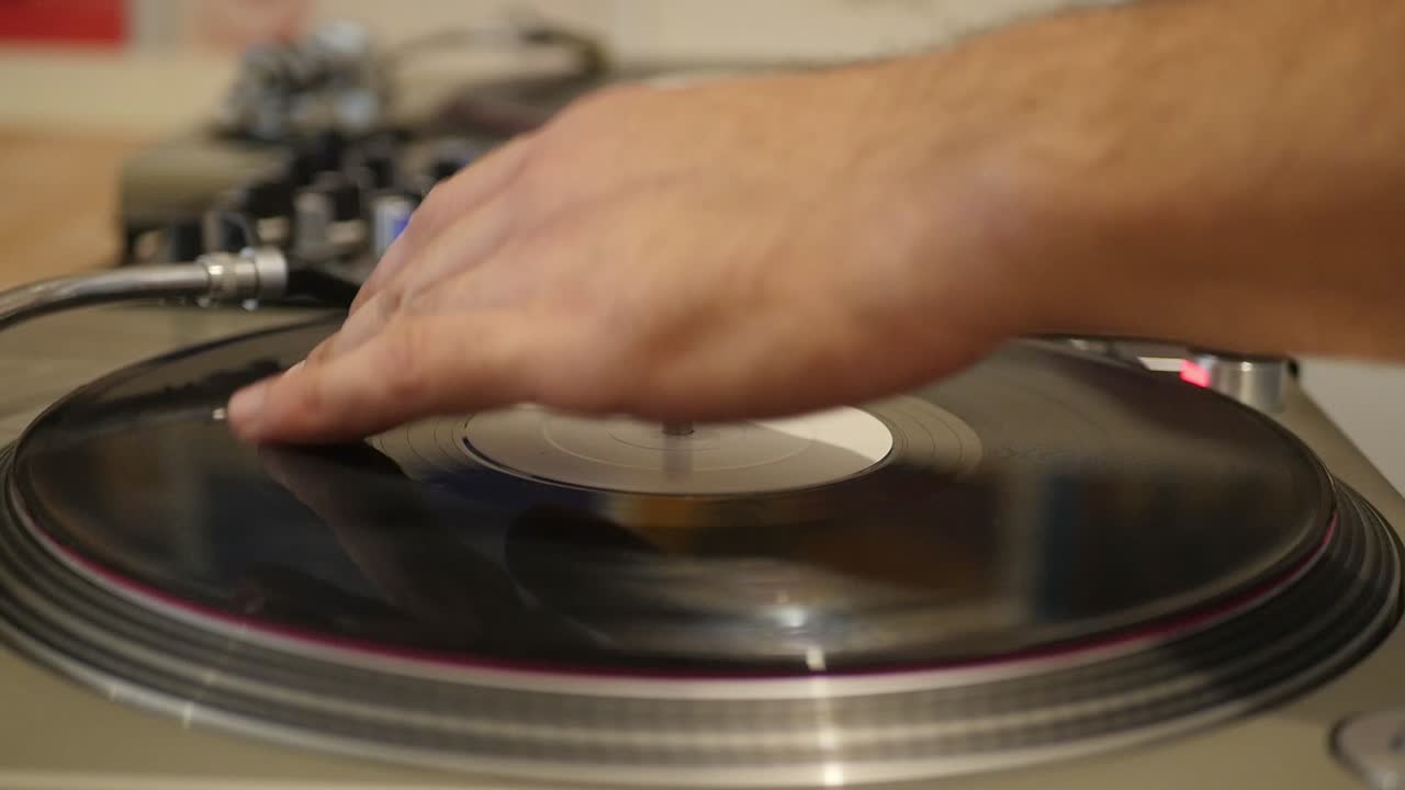 DJ Hands Close Up As He Mixes And Scratches Black Vinyl On A Turn Table
