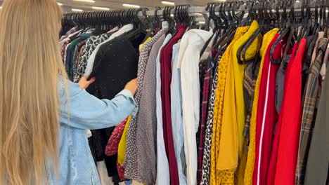 a girl in a vintage shop a young girl chooses things on a hanger in a store second hand a customer in a vintage store a young girl chooses things on a hanger in a store second hand shop cheap shop shop discounts