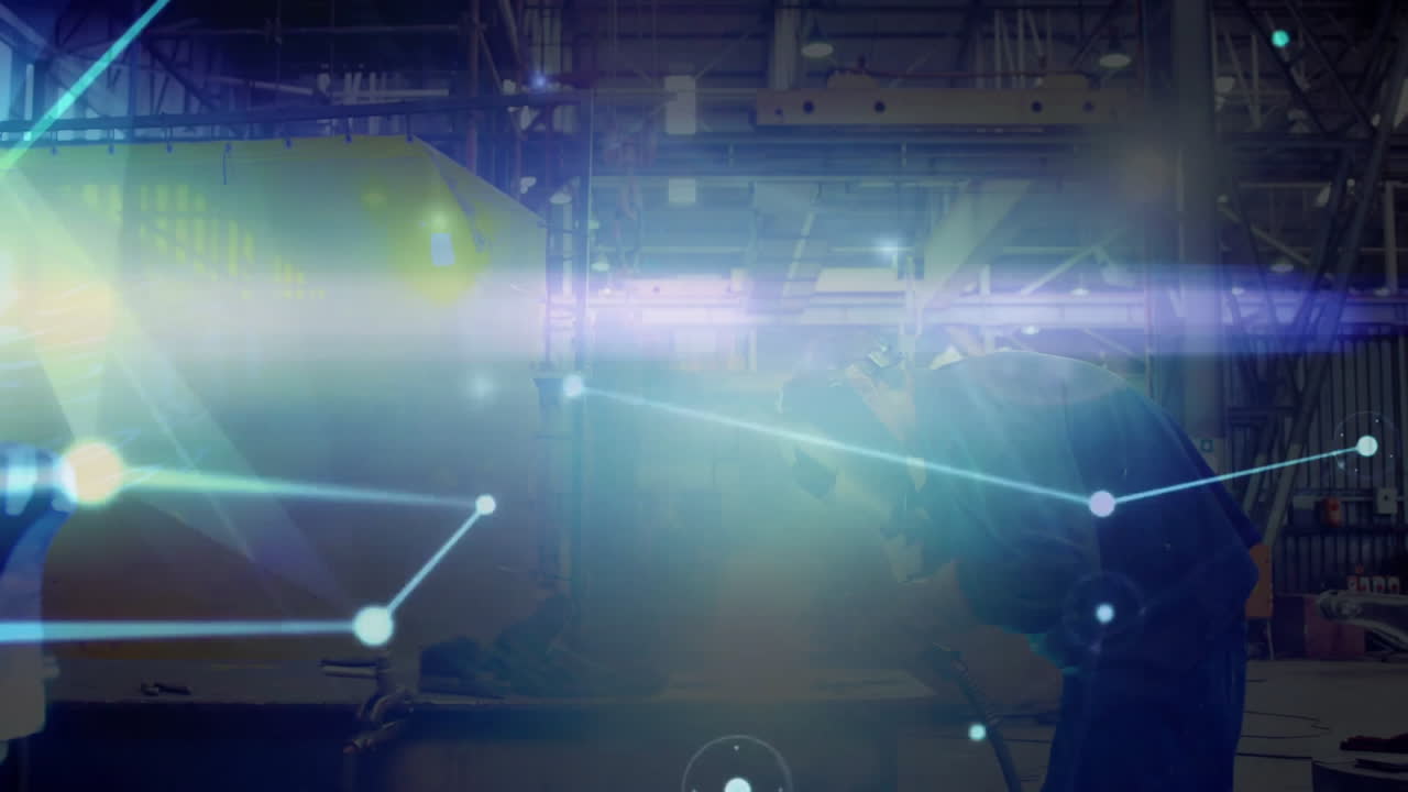 Factory worker welding with torch in manufacturing plant, blending sparks with data network overlay