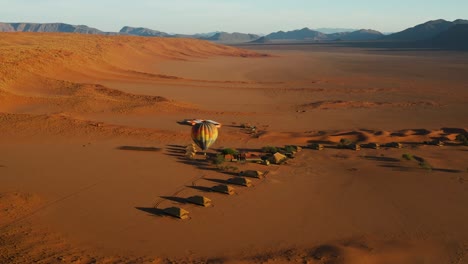 aerial zoom out view of a hot air balloon taking off from a safari lodge to fly tourists over the beautiful scenic namib desert, namibia