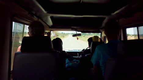 pov inside a 4x4 vehicle driving through dirt road in africa.