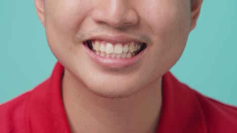 close up of portrait of attractive asian young man smiling and laughing in studio with isolate green screen in background. the man feeling happy and cheerful with positive attitude and thinking.