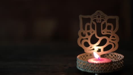 defocus bokeh out-of-focus closeup to a ganesha cutout with tea candle, or ganapati, vinayaka, or by numerous other names, is one of the best-known and most worshipped deities in the hindu pantheon.