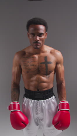 vertical video real time studio portrait shot of tattooed male boxer warming up before boxing match